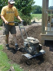 Marshall Warren is tilling the soil for preparation of planting.